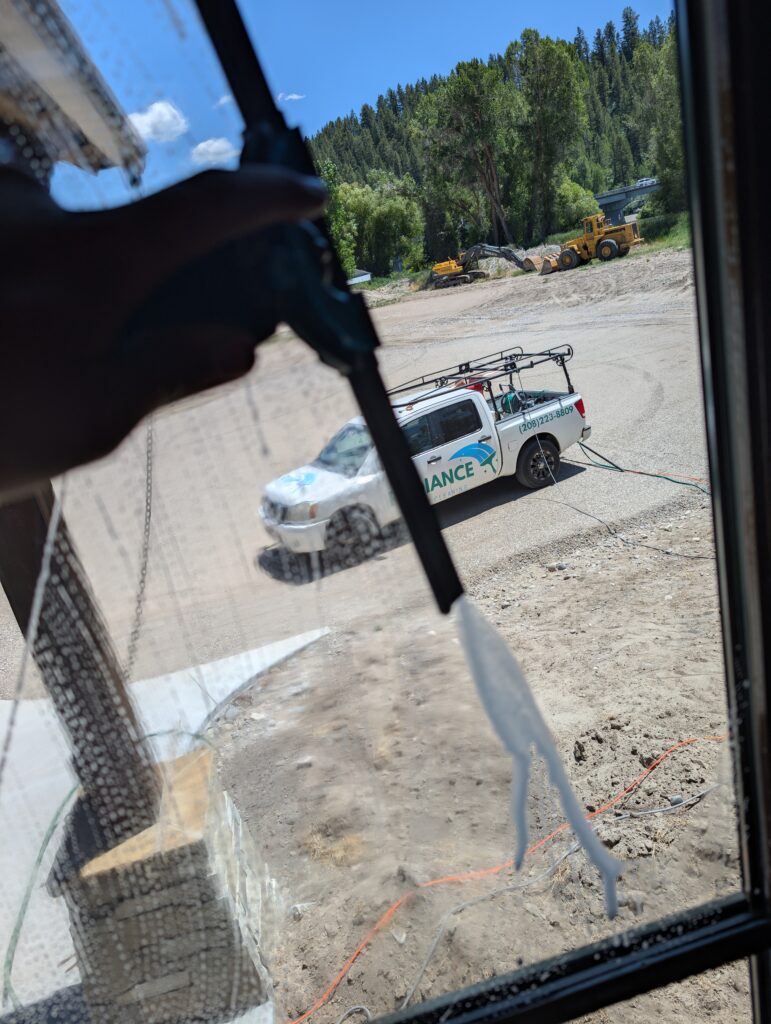 Window squeegee on glass with a Radiance Window Cleaning work truck parked outside, window cleaning service in Firth, Idaho